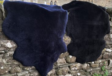 Black and navy short woolled sheepskin rugs draped over a wall